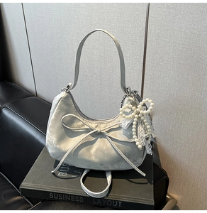 Détail du sac gris argenté avec pendentif nœud délicat en perles et dentelle blanche