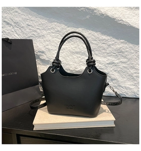 Detail of the black minimalist tote bag showing texture and detachable shoulder strap