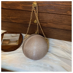 Detail of a champagne gold spherical evening bag with glittering texture and gold chain strap