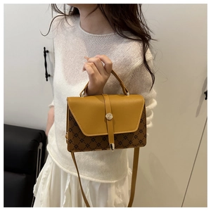 Detail of vintage crossbody bag with yellow flap and brown geometric pattern