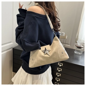 Détail d'un sac bandoulière blanc cassé avec boucle étoile argentée et rivets décoratifs
