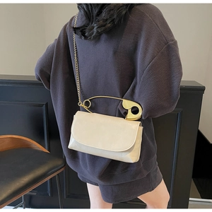 Sac bandoulière crème chic doté d'une poignée unique en forme d'épingle dorée