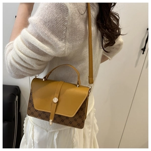 Side view of ginger yellow crossbody bag with vintage pattern and metal buckle
