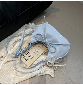 Détails du sac croissant bleu clair avec nœud en dentelle et pendentif en perles
