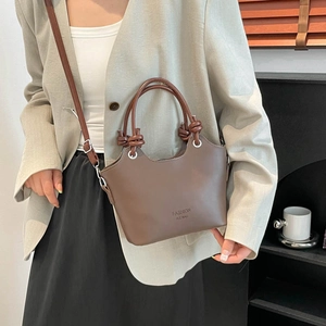 Minimalist brown leather bucket bag with knot handle and adjustable shoulder strap