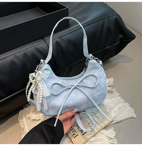 Détail du sac demi-lune bleu clair avec un nœud délicat et un pendentif perle