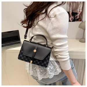 Crossbody bag with geometric pattern and gold buckle detail worn by a model