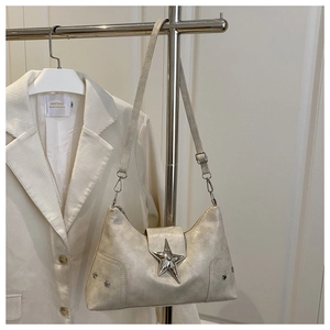 Détail du sac beige avec boucles en étoile argentées et texture en cuir craquelé vintage