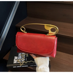 Détail du sac en cuir rouge texturé avec poignée épingle à nourrice dorée et bandoulière