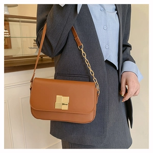 Detailed view of brown square shoulder bag with gold metal clasp and chain strap