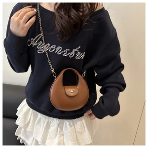 Sac bandoulière demi-lune marron avec chaîne dorée porté sur un sweat-shirt bleu marine