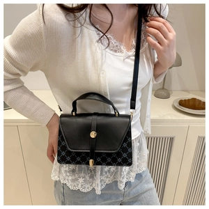 Detail of crossbody bag featuring black leather, quilted fabric, and clover pattern