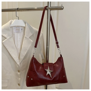 Détail d'un sac bandoulière en cuir rouge brillant avec boucle étoile argentée et rivets