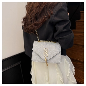 Detail of silver sequin crossbody bag with gold S-buckle tassel and chain strap