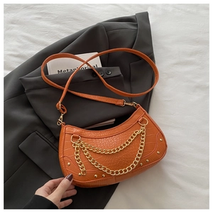 Détail du sac croissant orange en similicuir avec texture crocodile et chaîne dorée