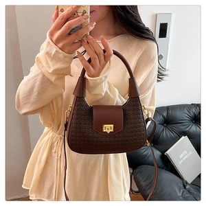 Close-up of brown woven texture shoulder bag with golden buckle and fixed top handle