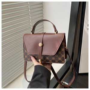 Detailed close-up of retro monogram pattern and magnetic buckle on the brown leather handbag