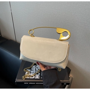 Détail d'un sac à main en similicuir crème avec une grande poignée en épingle dorée