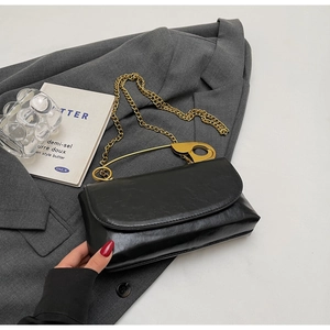 Détail du sac en cuir noir avec poignée en épingle à nourrice dorée et chaîne