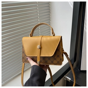 Detail view of mustard yellow faux leather handbag with vintage flower pattern and clasp