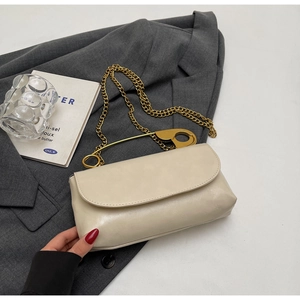 Détail du sac en cuir blanc crème avec une poignée unique en forme d'épingle à nourrice dorée