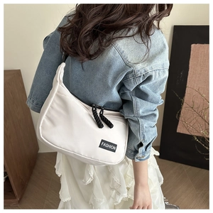 Detail of white nylon crossbody bag featuring dual black woven zippers and fashion label
