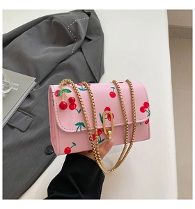 Detail showing pink cherry print bag with golden bead chain and cherry pendant accessory