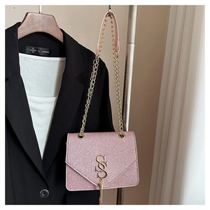 Pink glitter crossbody bag with gold chain strap and metal tassel detail on a hanger