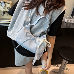 Sac hobo bleu clair avec nœud en dentelle et perles dans un décor de café