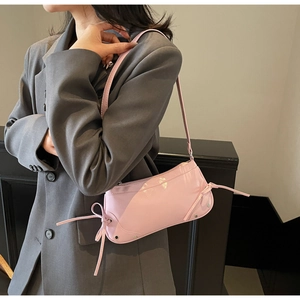 Close-up of pink patent leather shoulder bag with chic bow ties and silver metal rivets