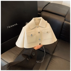 Macro shot of white jacket-shaped handbag featuring silver chain strap and mini button detail