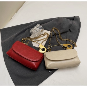 Détail de sacs bandoulière rouge et beige avec poignée épingle dorée sur blazer