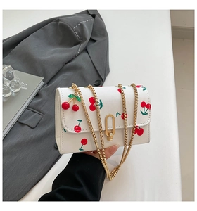 Detail of white PU shoulder bag featuring cherry print, gold chain and U-shaped lock
