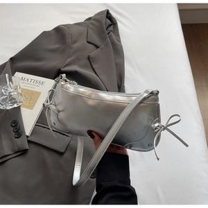 Close-up of metallic silver shoulder bag featuring a stylish side bow and zipper detail