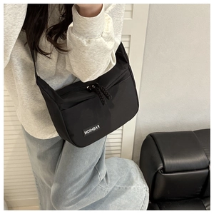 Adjustable strap and fashion label detail on a large minimalist black messenger bag