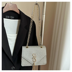 Detailed close-up of a silver glitter crossbody bag with gold chain and metal S logo