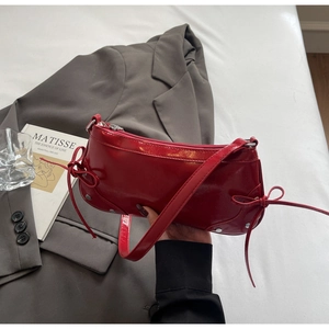 Detail of red patent leather shoulder bag with side bow accents and silver zipper