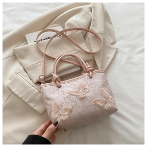 Dettaglio della borsa in pizzo rosa con squisiti ricami di farfalle in rilievo