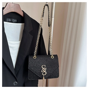 Detail of black glitter small crossbody bag with golden SS logo and long tassels