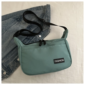 Dettaglio della borsa a tracolla in nylon verde menta con etichetta FASHION nera