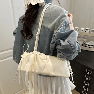 Schicke weiße Schultertasche mit Spitzenschleife und Seidenband an einem Modell