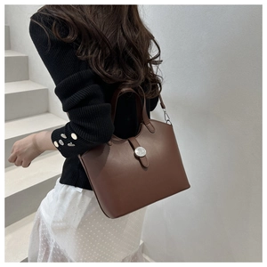 Detail view of the deep brown leather tote bag with a round metal clasp in a stylish setting
