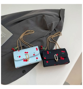 Detail of light blue and black mini cherry print crossbody bags with golden chain straps