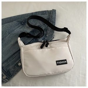 Dettaglio della borsa messenger in nylon bianco con tracolla nera ed etichetta