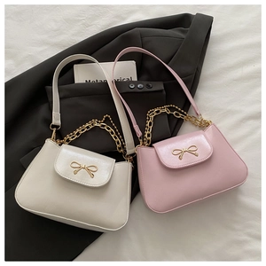 Close-up of pearl PU leather bag with golden bow buckle on grey suit jacket
