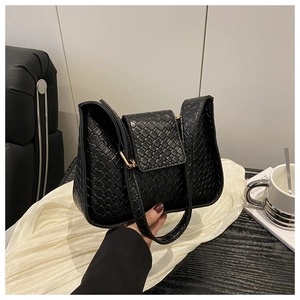 Détail de la texture tressée du sac à main noir avec boucle métallique dorée