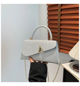 Close-up of glitter silver shoulder bag with gold V-clasp and metallic chain strap