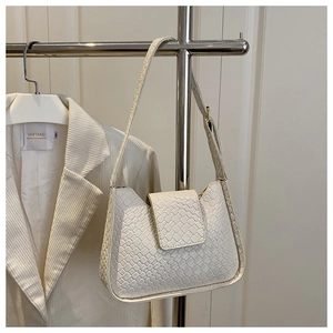 Détail de la texture tressée et du rabat d'un sac à bandoulière hobo blanc élégant