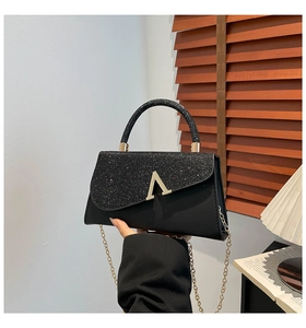 Close-up of black crossbody bag with sequined flap and golden V-shaped metal buckle