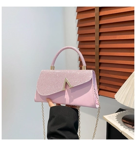 Detail of pink evening bag featuring rhinestone flap and golden V-shaped buckle hardware